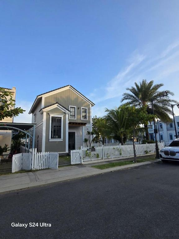 a white house with a white fence and palm trees at Phan Thiết Nova World Malibu 2 Villa in Phan Thiet