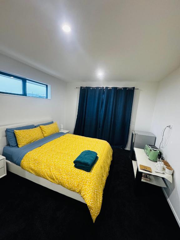 a bedroom with a yellow bed with a blue curtain at Room with en-suite bathroom in Kaiapoi