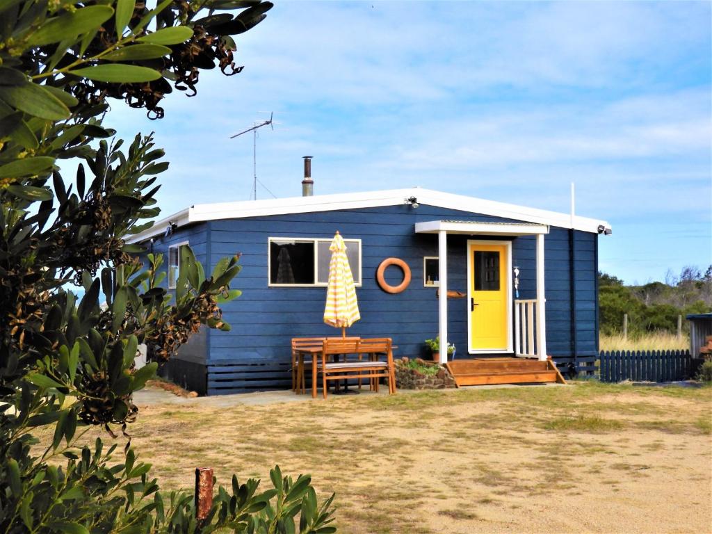 a blue tiny house with a yellow door at Driftwood Cottage in Dolphin Sands