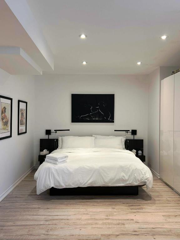 a white bedroom with a large bed with a tv on the wall at Luxury Executive Studio in Oakville
