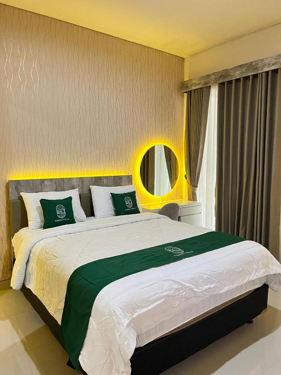a bedroom with a large bed with green and white pillows at Sampai Villa Vasana in Yogyakarta