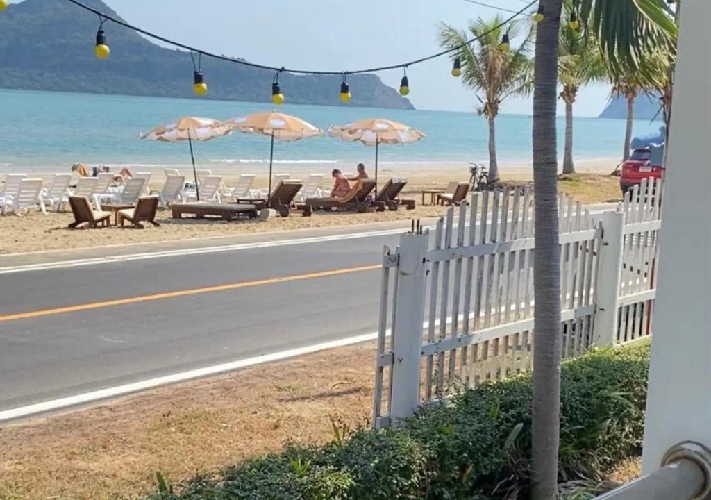 a road with chairs and umbrellas on the beach at Baan Golden Resort & Residences in Sam Roi Yot