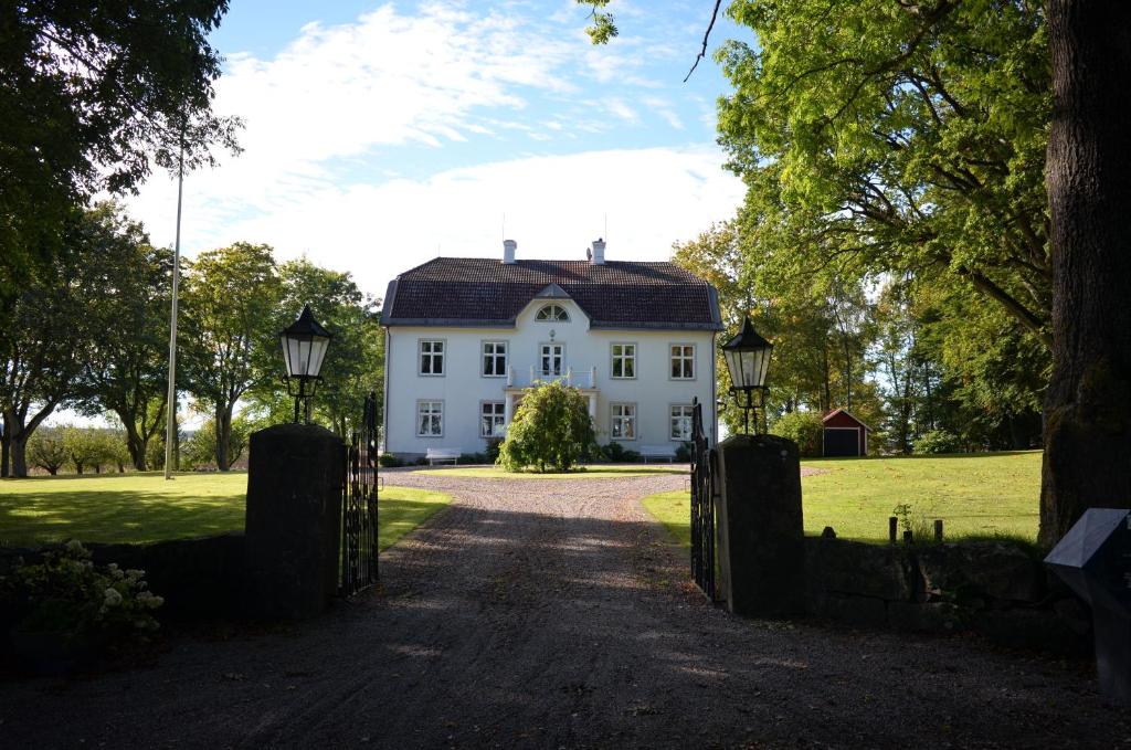 Uma casa branca com um portão à frente. em Södra Lund B&B em Vreta Kloster