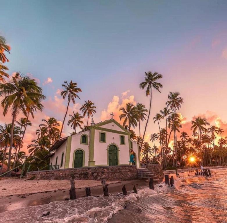 a small building on the beach with palm trees at Casa Refúgio Tamandaré in Tamandaré