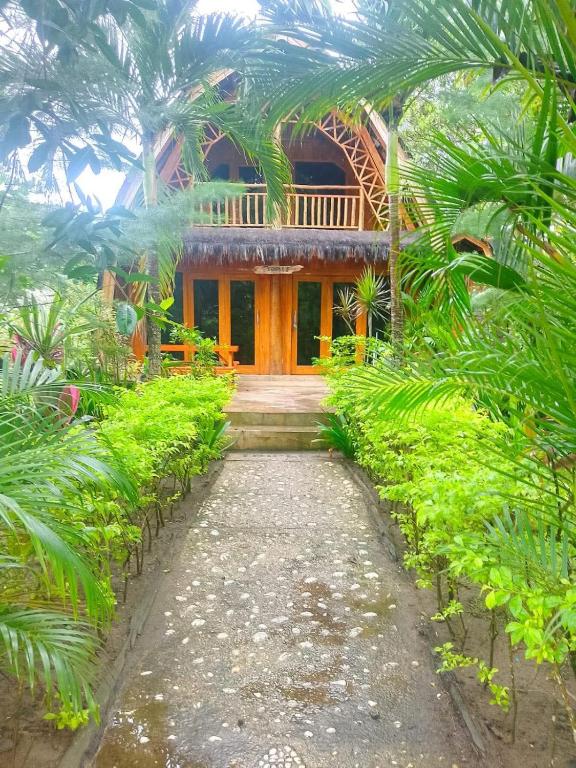 a walkway leading to a house with palm trees at Triple J Villa in Sekongkang Bawa