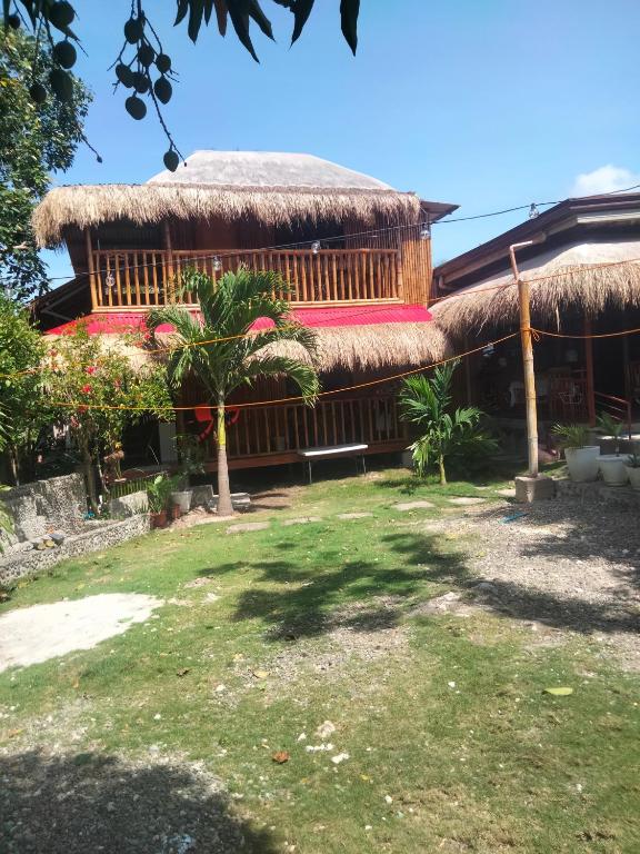 a building with a thatched roof with a grass at The Garden Tropical Cabins in Basdiot