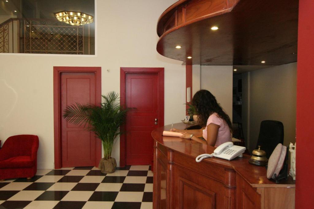 a woman sitting at a counter with a phone at Hotel Palladion in Ermoupoli