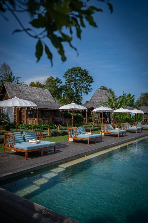 a pool with lounge chairs and umbrellas next to a resort at Umah Lusa in Munduk