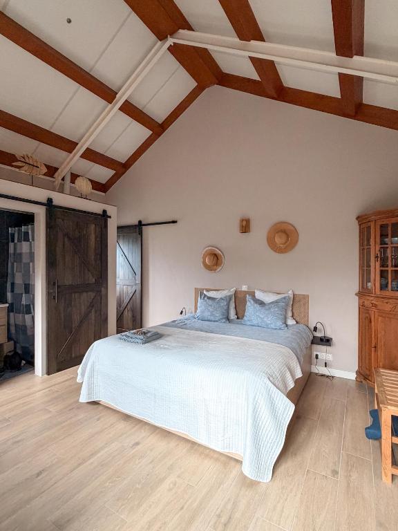 a bedroom with a large bed and wooden ceilings at Sea You Soon in Callantsoog