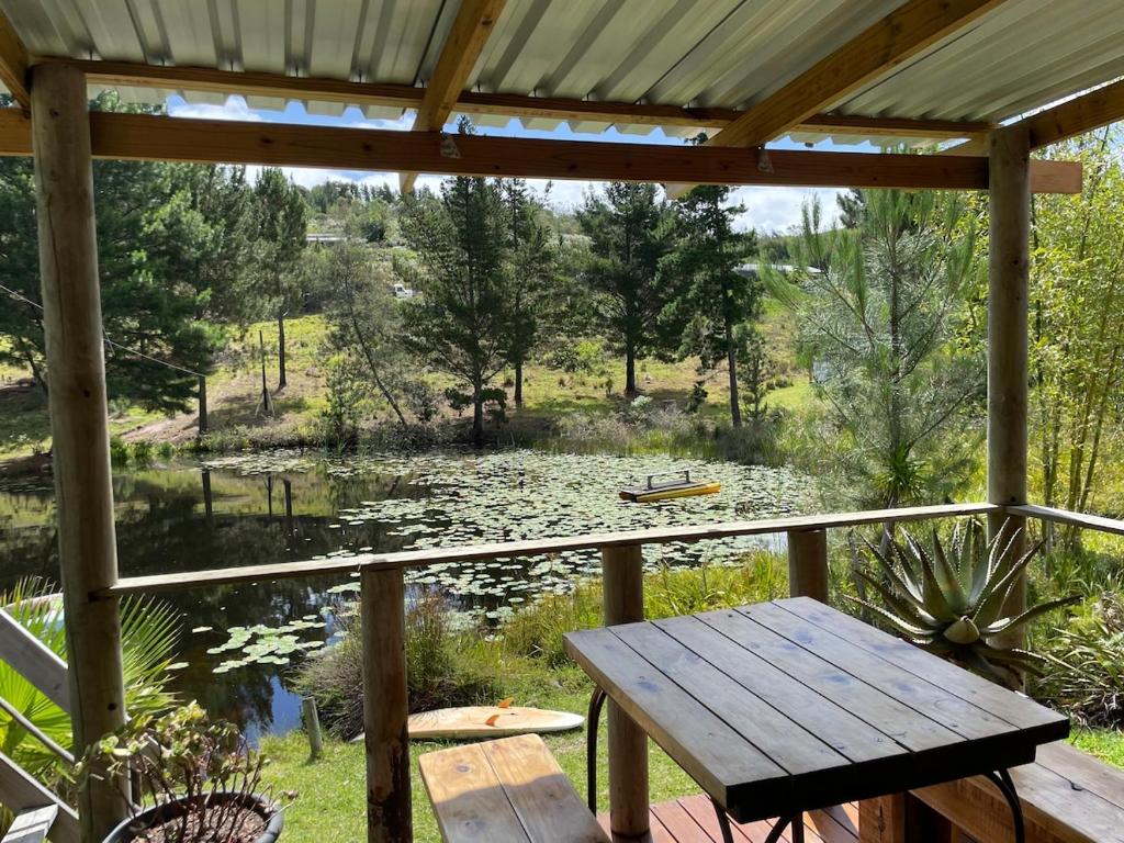 a porch with a table and a view of a pond at Olivias Cottage in Knysna