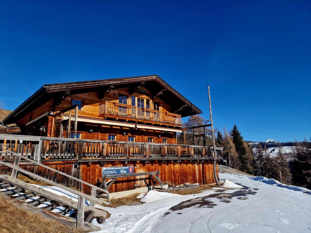 a large log cabin in the snow with a balcony at Faschingalm Loft in Lienz