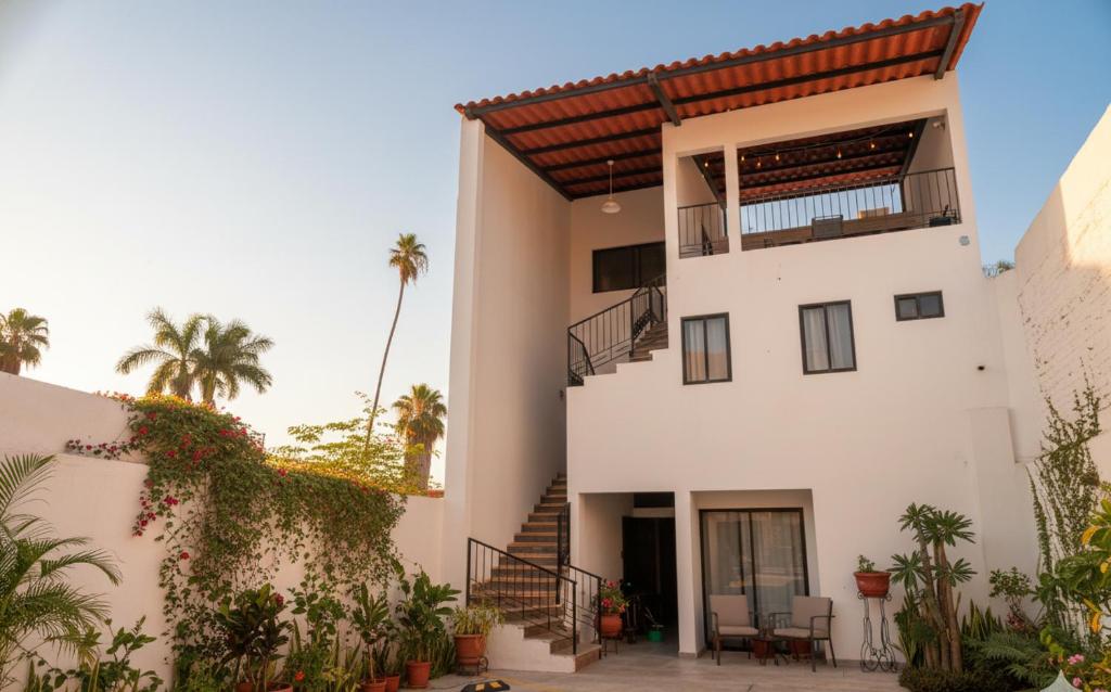 a white house with a balcony and palm trees at Casa Rosales in Los Mochis