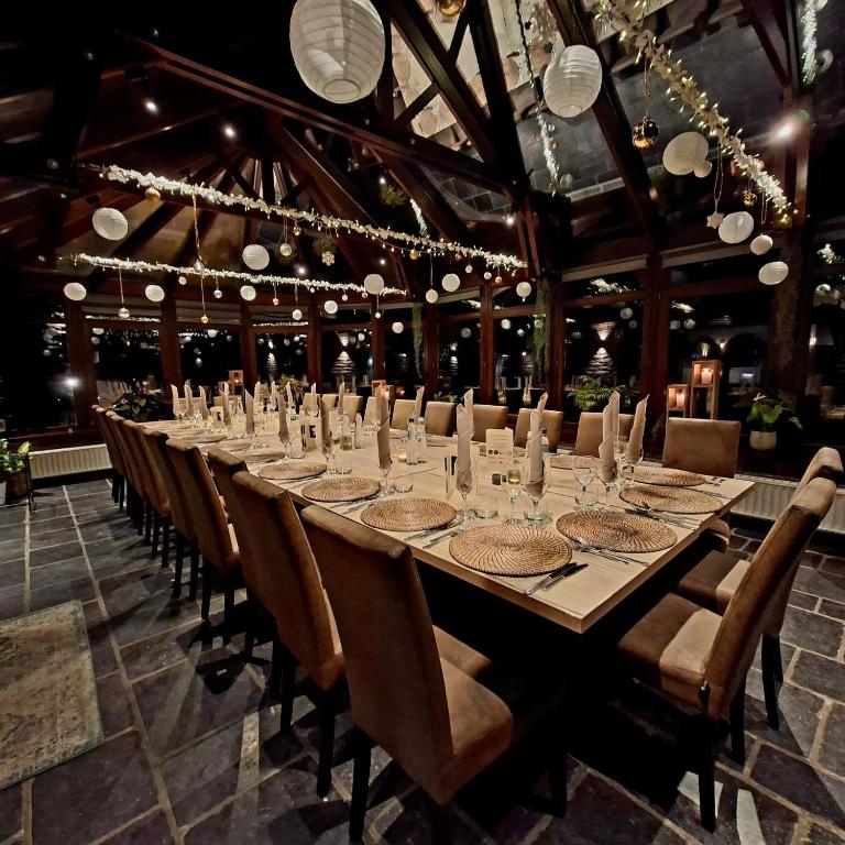 a long table in a room with chairs and lights at Hotel-Restaurant La Crémaillère in Jalhay