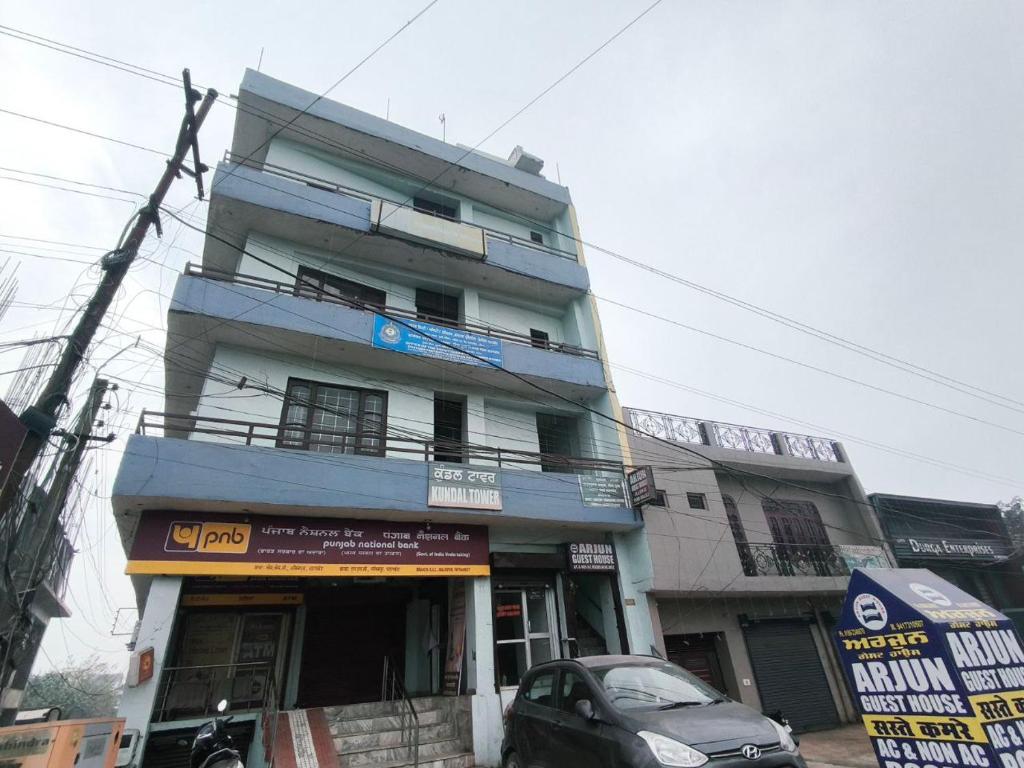 a tall building with a car parked in front of it at Arjun House Hotel- Guest House in Pathānkot