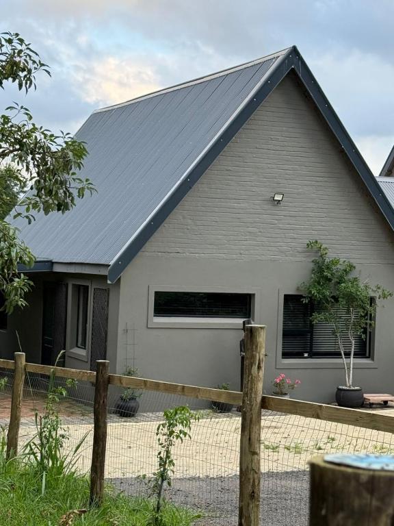 a house with a gray roof and a fence at Avo 2 on 27 Drew in Howick