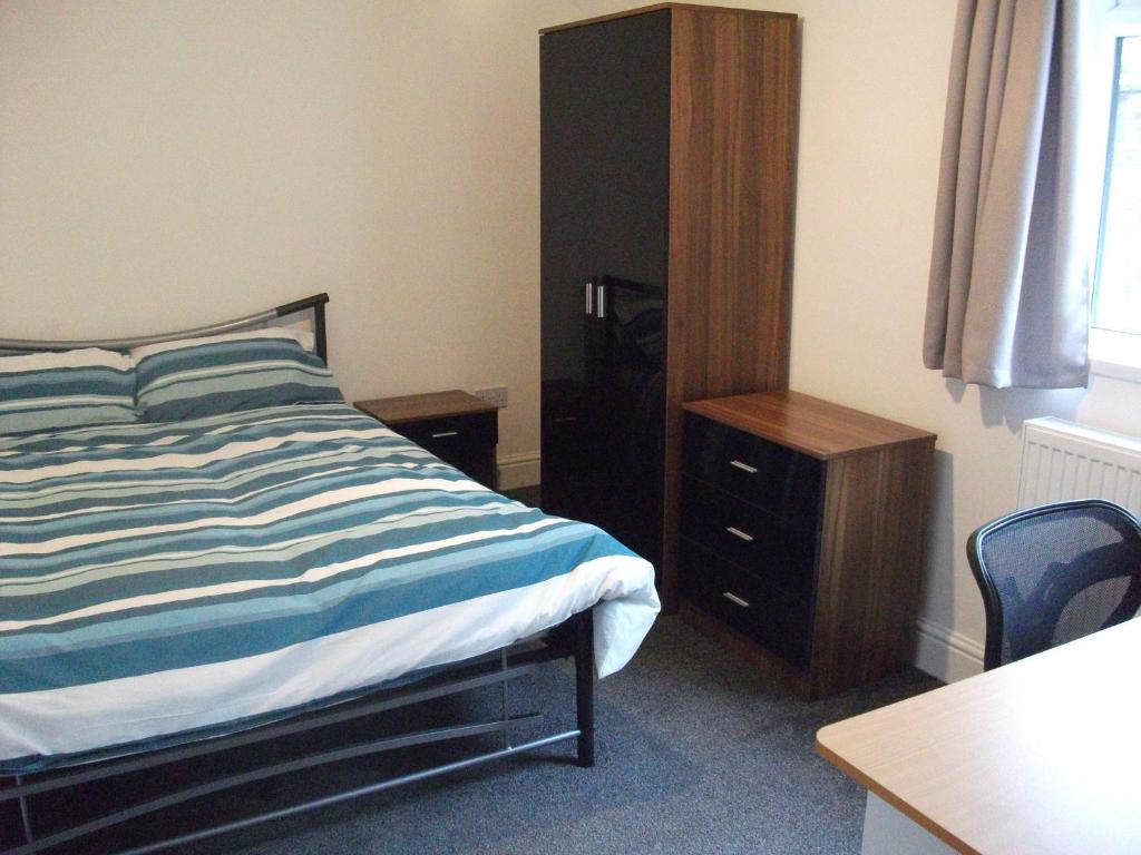 a bedroom with a bed and a desk and a cabinet at The Grange in Middlesbrough