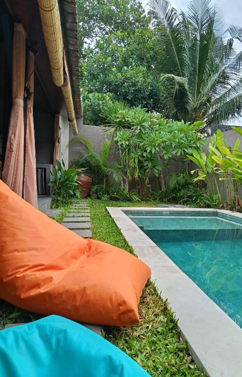 an orange pillow next to a swimming pool at Villa Lottie Sanur in Sanur