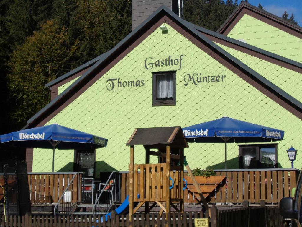 ein grünes Gebäude mit einem Spielplatz davor in der Unterkunft Gasthof Thomas Müntzer in Steinheid