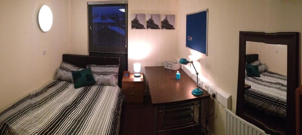 een slaapkamer met 2 bedden, een bureau en een spiegel bij Alton Apartments in Bradford