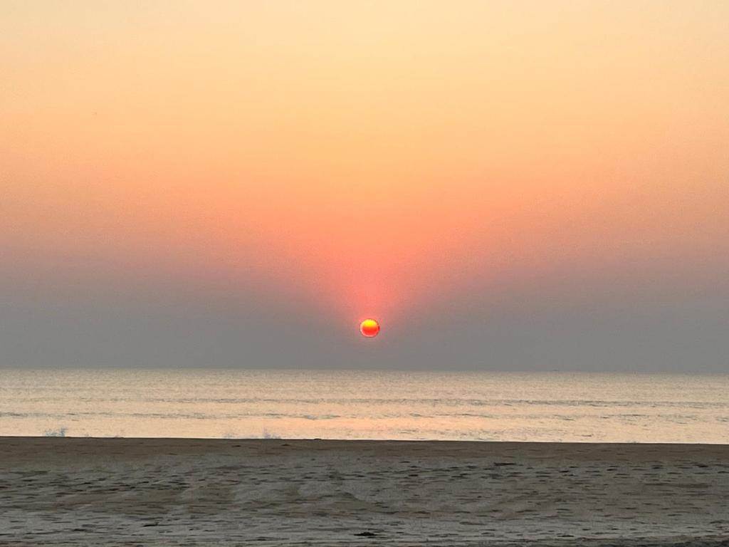 a sunset on the beach with a person walking on the beach at Arabian Breeze in Tadri
