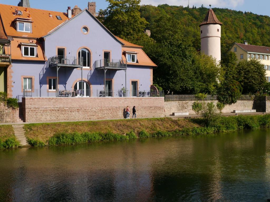 two people walking by a building next to a body of water at Tauberterrasse in Wertheim
