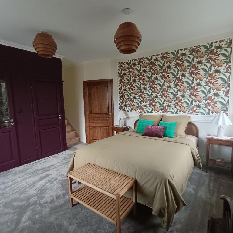 a bedroom with a large bed and a floral wall at Les chambres du Lohan in Daoulas