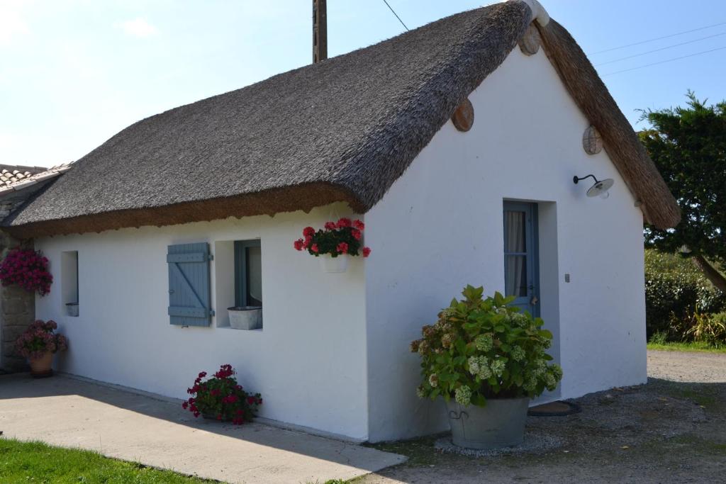 een wit huisje met een rieten dak bij Les Pensions du Joslin in Bouin