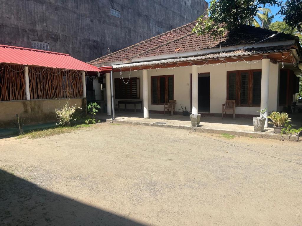 a small house with a red roof and a building at Cattleya Guest House in Tissamaharama