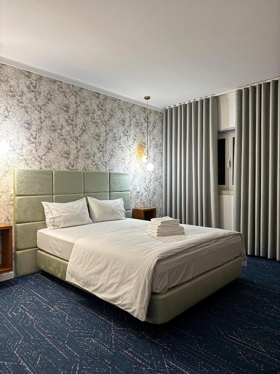 a bedroom with a large bed with a green headboard at White Guest in Fátima