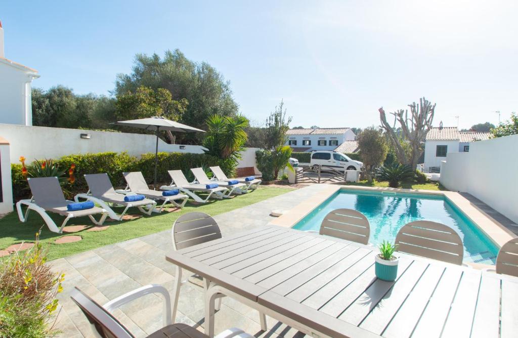 a patio with a table and chairs and a pool at Villa Can Canaleta by Sonne Villas in Cala Galdana