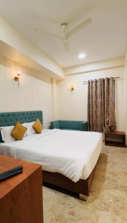 a bedroom with a large white bed and a couch at Hotelgirdharinn in Indore