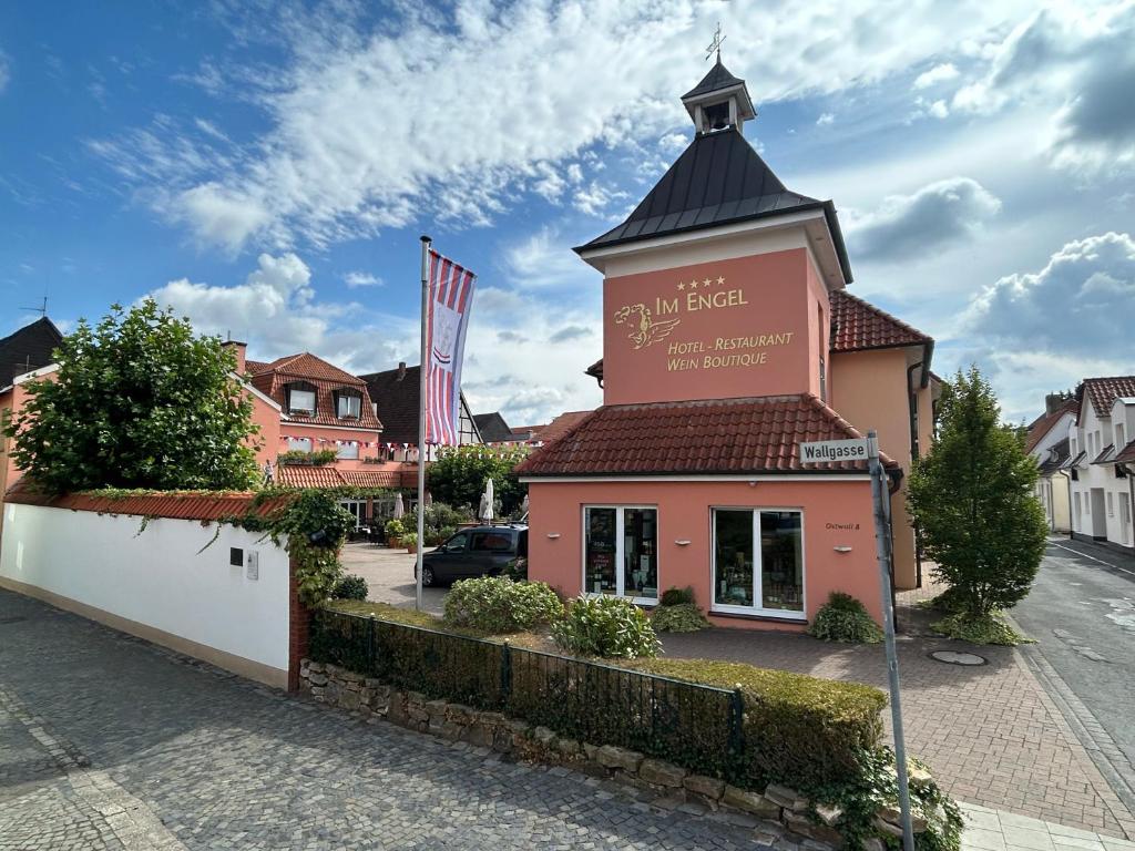 ein kleines rosa Gebäude mit einem Turm an einer Straße in der Unterkunft Hotel Im Engel in Warendorf