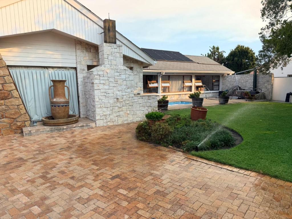 a house with a brick driveway in front of a yard at Layover on Loerie in Cape Town