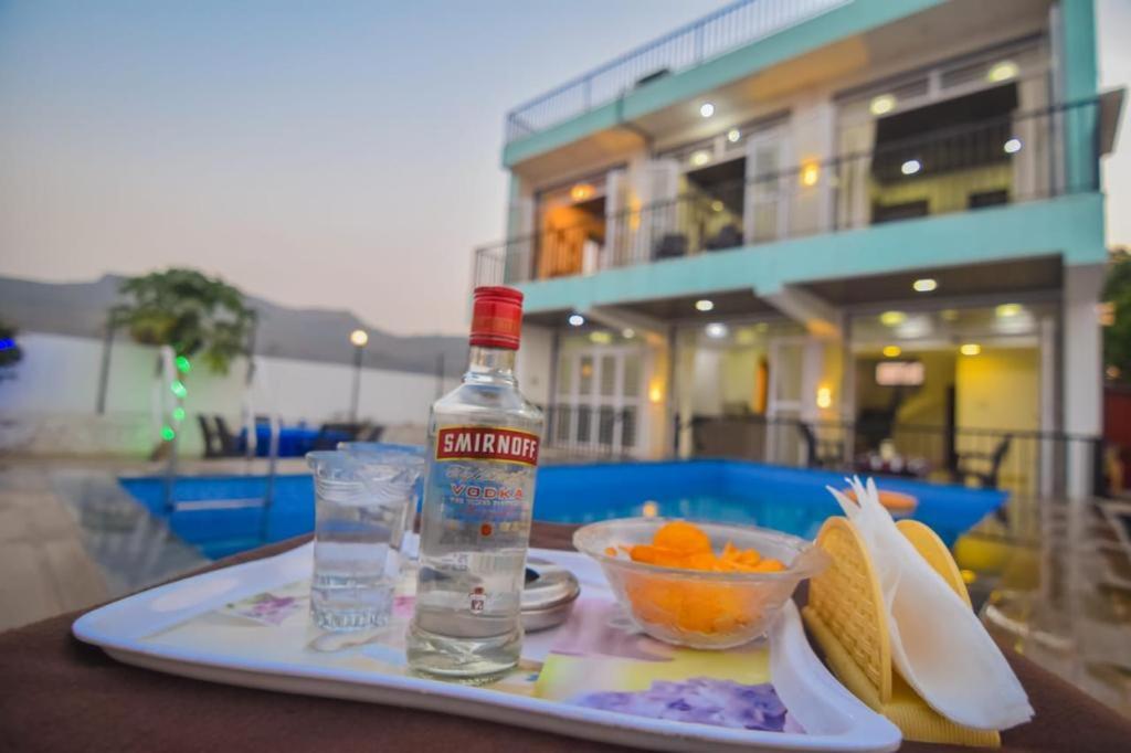 a bottle of alcohol and a bowl of fruit on a tray at ll EMPYREAN STAY ll LUXE ll FORTUNE VILLA ll 4BHK ll AC ll BIG POOL in Lonavala
