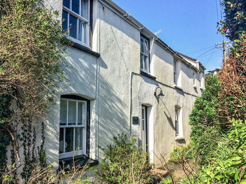 a white brick house with windows and bushes at Fuchsia Cottage in Saint Mawes