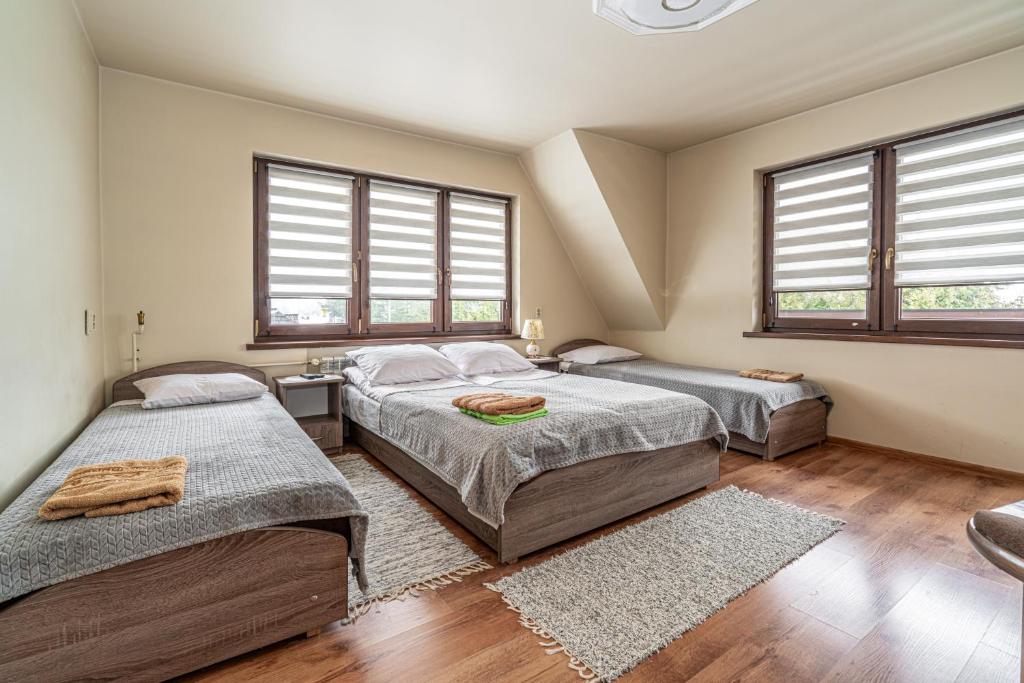 a bedroom with two beds and two windows at Dom Na Borku Józefa Schulz in Ciche