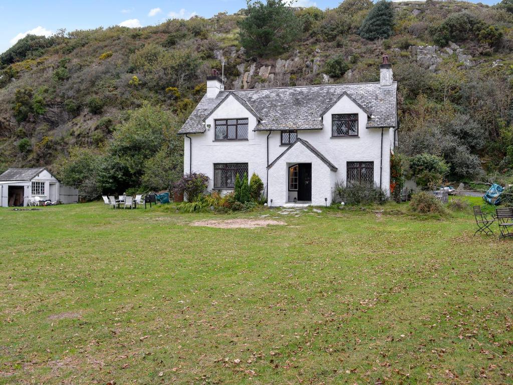 a white house in a field with a hill at Llys Cyngar in Porthmadog