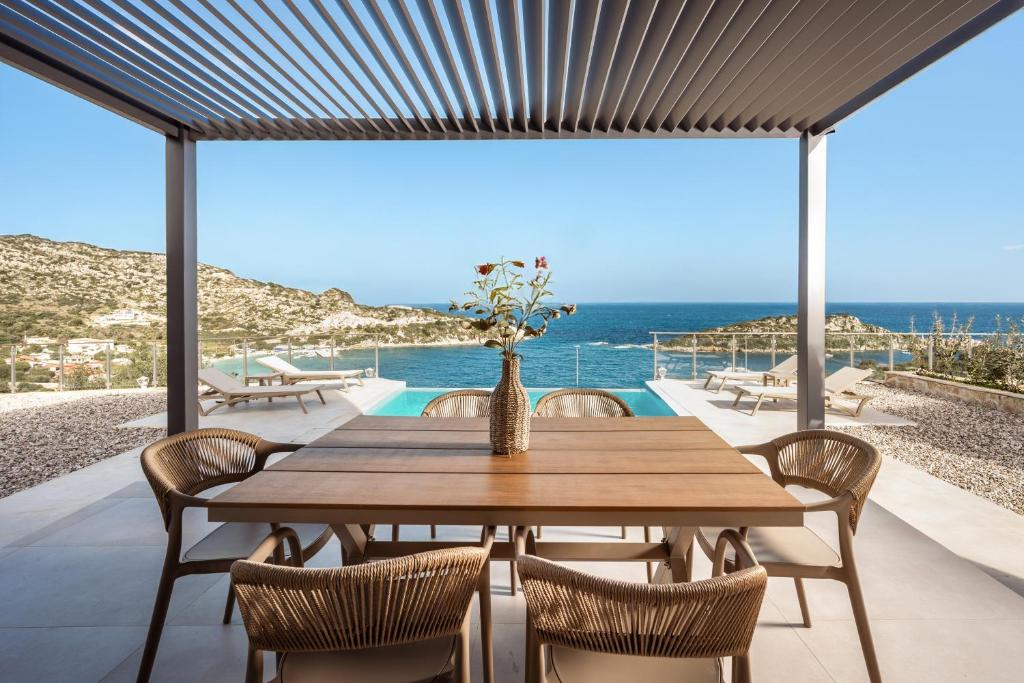 a dining room with a table and chairs and the ocean at Ventalia Villas, 3BR Sea View and Infinity Pool by Villa Mana Gers in Agios Nikolaos