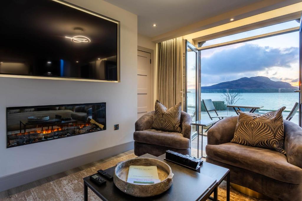 a living room with two chairs and a fireplace at Arran Shores Luxury Shorefront Suite 1 in Lamlash