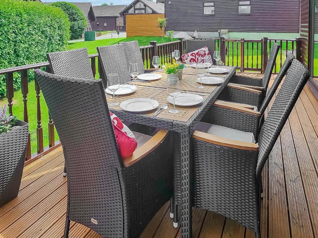 an outdoor table with wicker chairs on a deck at Beech Lodge - Retallack Resort in Saint Columb Major