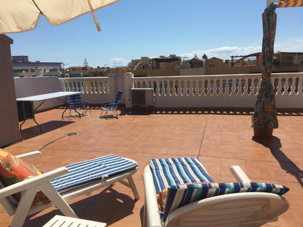 a patio with chairs and an umbrella and a table at Xaloc Solo Familias Serviplaya in Playa de Xeraco