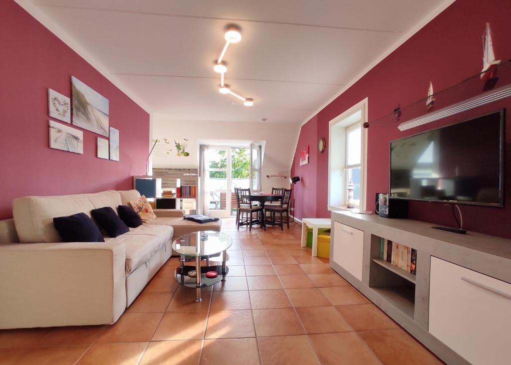 a living room with a white couch and a tv at Ostseeliebe in Kirchdorf