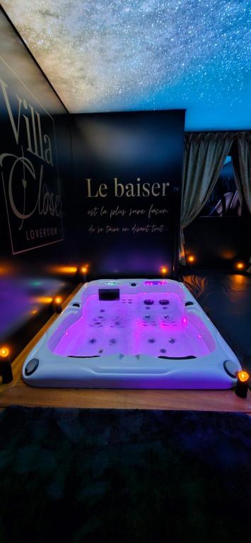 a room with a hot tub with purple lights at VILLA CLOSE BRIVE centre - LOVE ROOM - SPA privatif in Brive-la-Gaillarde
