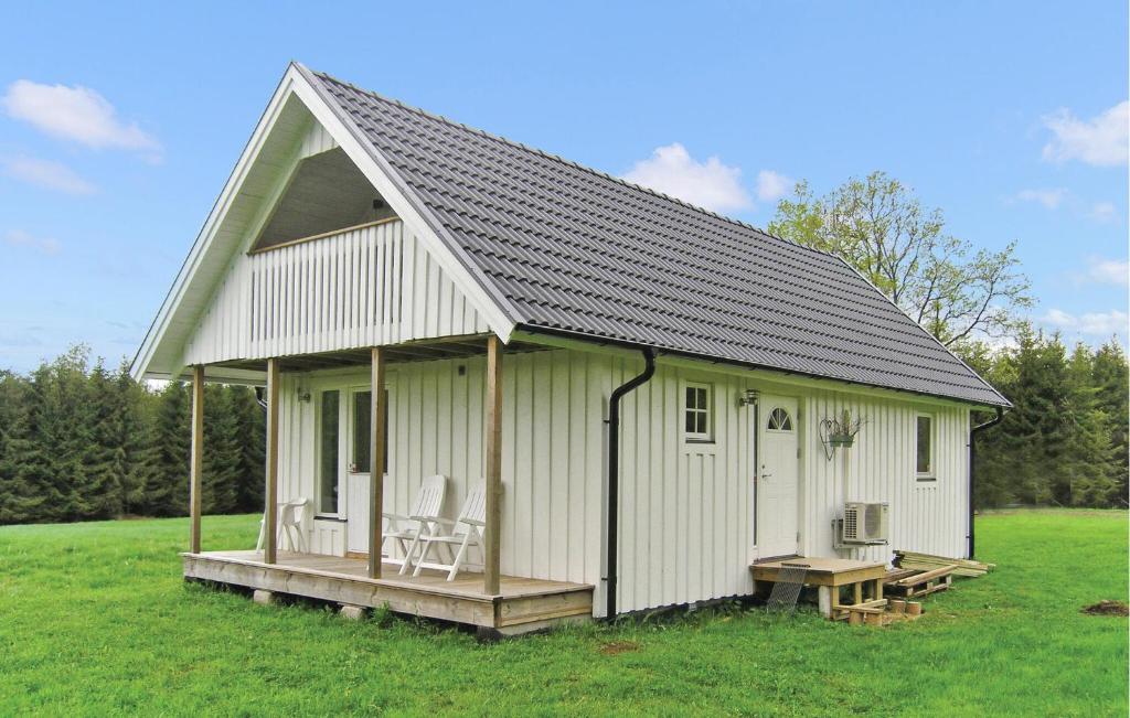 a white shed with a porch and chairs in a field at Amazing Home In Burseryd With Kitchen in Burseryd