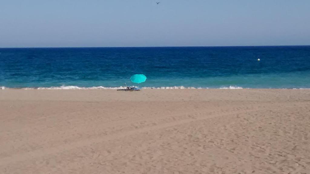 un ombrellone blu seduto su una spiaggia vicino all'oceano di Casita Andaluza a San Luis de Sabinillas