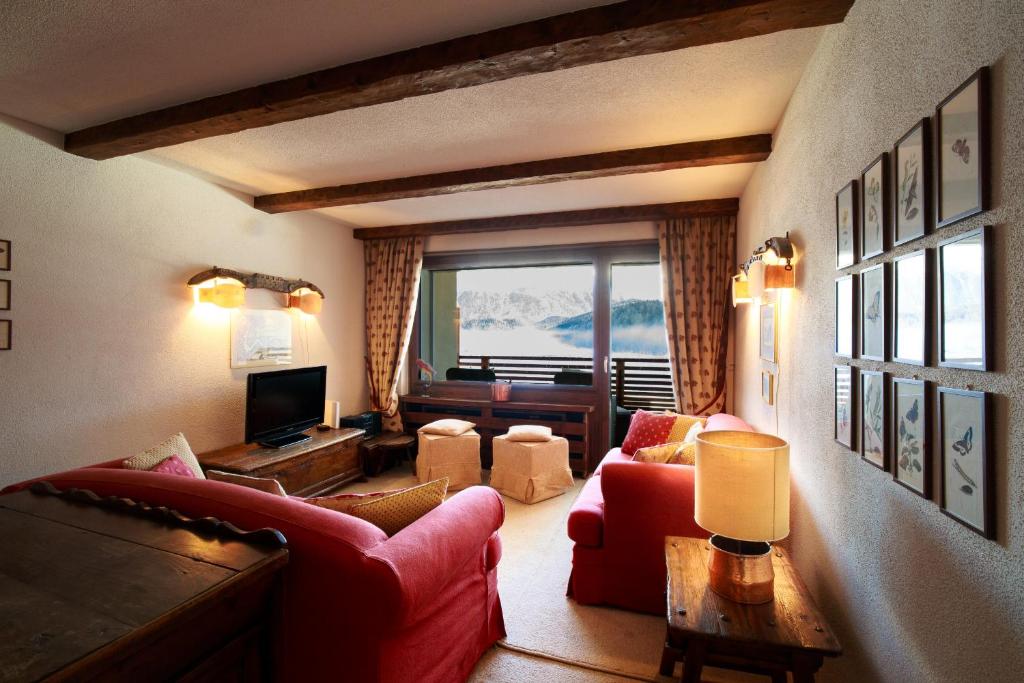 a living room with red furniture and a large window at Chesa Cuntainta B 4pax - St Moritz in St. Moritz