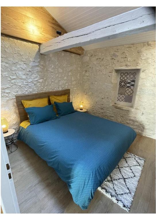 a bedroom with a blue bed in a stone wall at La Pierre Pourpre in Eymet