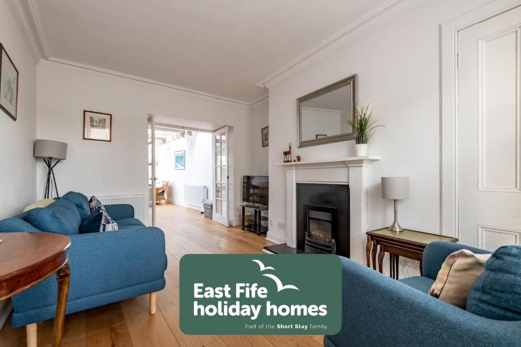 a living room with two blue couches and a fireplace at School Wynd No 6 - Elie in Elie