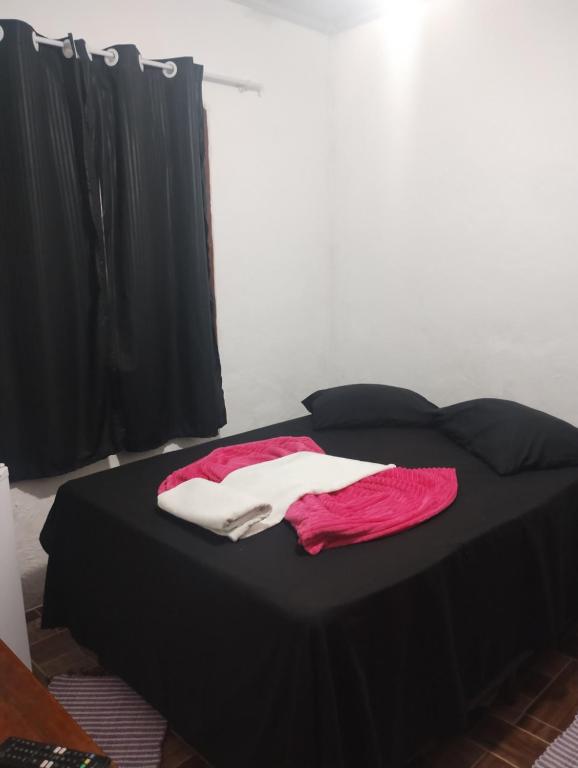 a black bed with pink and white towels on it at Hostel Raio de Fogo in Paraty