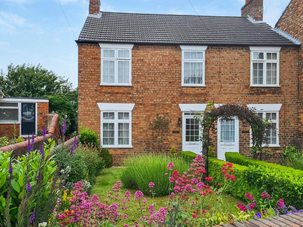a brick house with a garden in front of it at Lavender Cottage in Louth